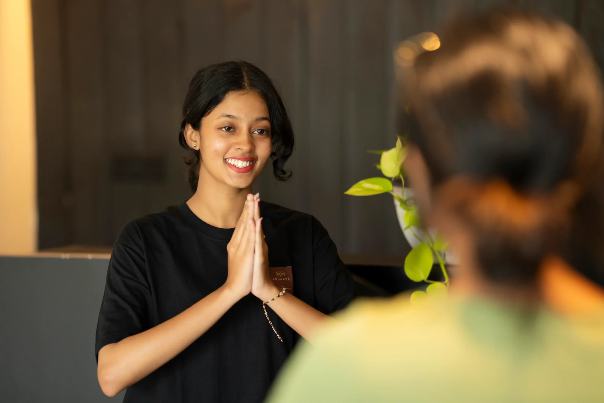 Sri Lankan therapist greeting a female guest with a warm smile and traditional gesture at Aksaaya Ayurveda Spa Colombo Sri Lanka